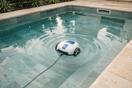 Robot de piscine autonome nettoyant le fond d'une piscine rectangulaire extérieure avec de l'eau turquoise claire